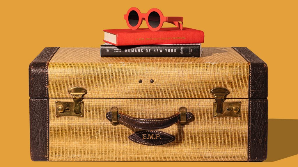 Suit case with two books on top with red sun glasses